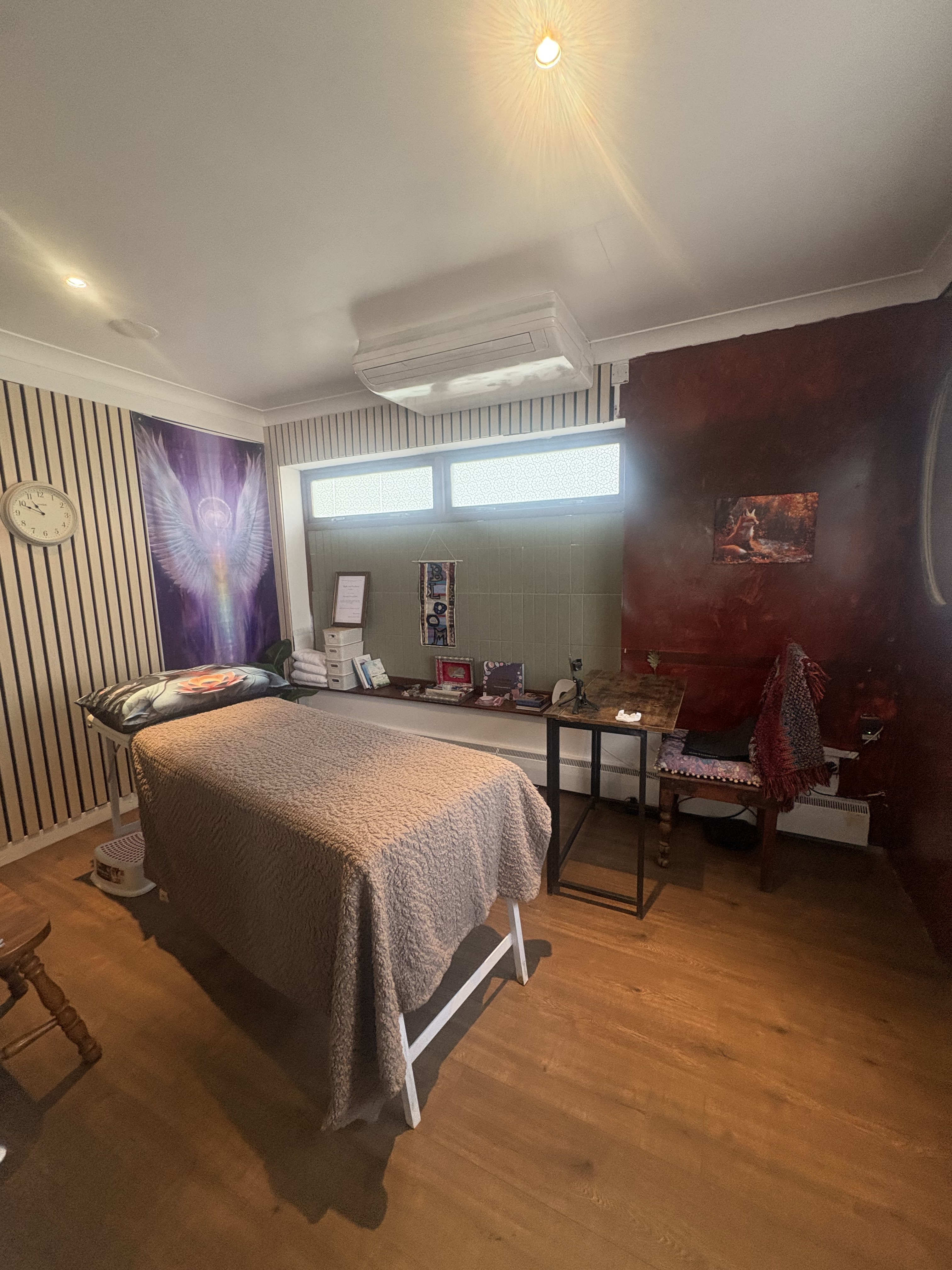 Warm private treatment room with a prepared massage table, soft lighting and spiritual artwork